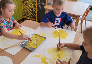 Dzieci malują żółtą farbą.