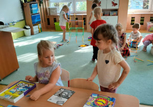 Dwie dziewczynki bawią się przy stoliku wykorzystując grę edukacyjną.