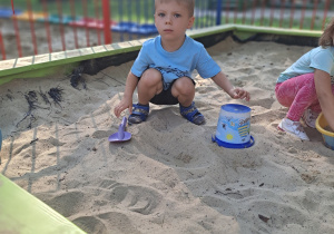 Chłopiec bawi się w piaskownicy