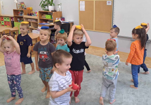 Dzieci starają się utrzymać woreczek gimnastyczny na głowie.