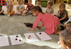 Dzieci wykorzystują kasztany podczas matematycznych zadań.