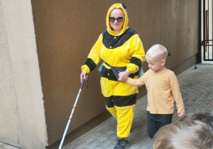 Chłopiec pomaga Pszczółce bezpiecznie poruszać się po dziedzińcu fundacji.
