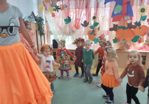 Dzieci tworzą wspólnie wężyk i tańczą do jesiennej piosenki.