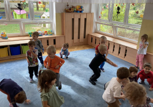 Dzieci tańczą na dywanie.