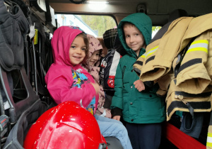 Dzieci zwiedzają wnętrze wozu strażackiego.