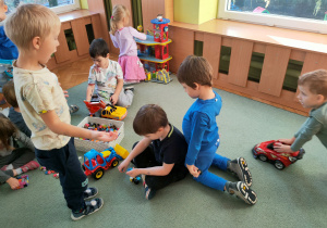 Dzieci bawią się zabawkami na dywanie.