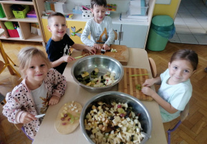 Dzieci dodają pokrojone kawałki do miski.