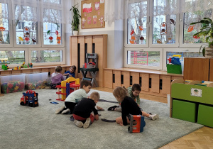 Dzieci spędzają wspólnie czas na zabawie na dywanie.