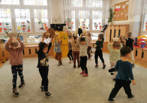 Dzieci biorą udział w zabawie ruchowej wspólnie ze swoimi maskotkami.