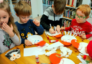 Dzieci tworzą pracę z wykorzystaniem papierowych talerzyków.