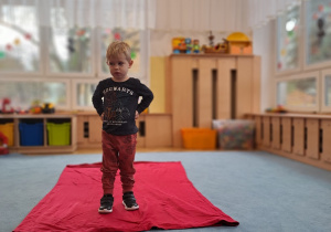 Chłopiec prezentuje na czerwonym dywanie swoją piżamę.