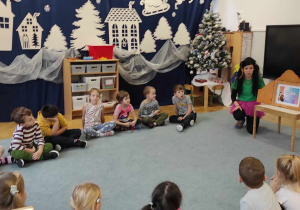 Dzieci słuchają opowiadania czytanego przez nauczyciela.