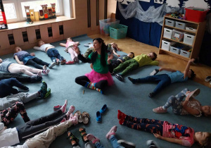 Dzieci odpoczywają po zajęciach na dywanie.