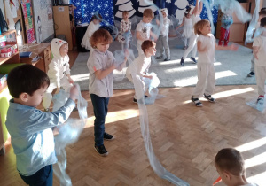 Dzieci tańczą trzymając w rękach materiałowe szale.