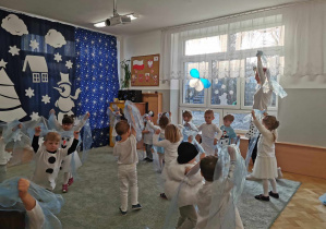 Dzieci tańczą z błękitnymi chustkami.