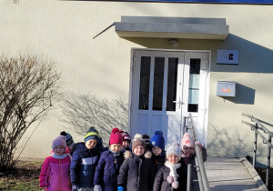 Dzieci stoją przed wejściem do biblioteki.