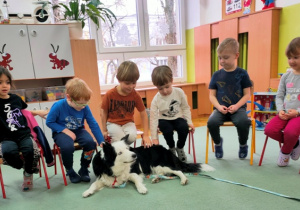 Po zajęciach dzieci głaszczą psiego terapeutę.