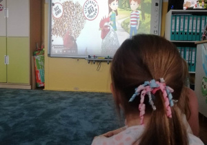 Dzieci oglądają film edukacyjny o produktach ekologicznych.