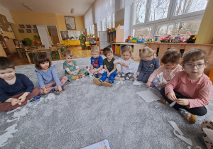 Dzieci siedzą na dywanie i robią doświadczenia