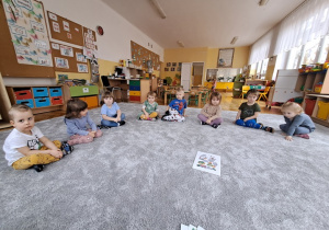 Dzieci siedzą na dywanie i odpowiadają na pytania dotyczące czystego powietrza