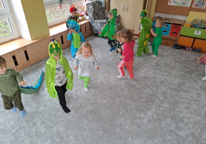 Dzieci biorą udział w zabawach ruchowych na dywanie organizowanych przez nauczyciela.