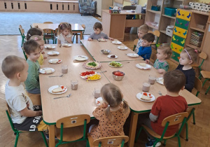 Dzieci siedzą przy stołach.