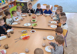 Dzieci siedzą wspólnie i zastanawiają się z czym zjeść kanapeczki na śniadanie.