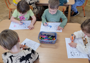 Dzieci kolorują dinozaury według własnego pomysłu.