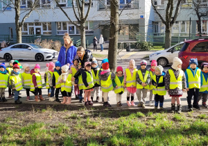 Dzieci obserwują pierwsze kwiaty rosnące w okolicy biblioteki miejskiej.