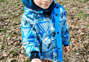 Chłopiec trzyma w ręku kiełkujące kasztany.