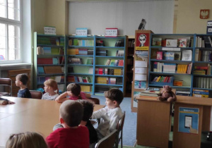 Dzieci słuchają opowiadań Pani dotyczących wyposażenia biblioteki, czytania książek.