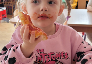 Dziewczynka je pizzę.