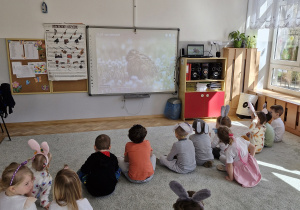 Dzieci oglądają film edukacyjny nt. zajączków.