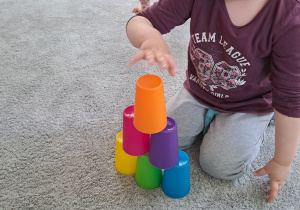 Dziewczynka układa wieżę z kubeczków.