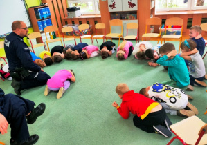 Dzieci ćwiczą na dywanie pozycję "żółwia".