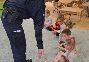 Dzieci przybijają piątki z policjantką.