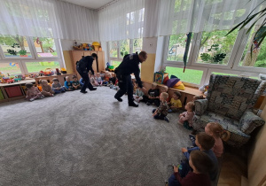 Funkcjonariusze Policji przybijają piątkę z kolejnymi dziećmi.