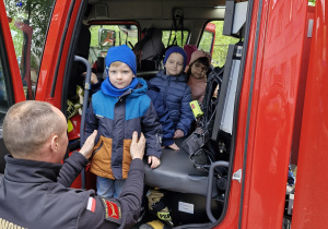 Dzieci wysiadają z wozu strażackiego.