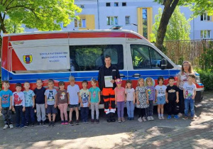 Zdjęcie grupowe na tle pojazdu medycznego.