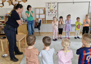 Pani omawia z dziećmi bezpieczną pozycję podczas spotkania z groźnym psem.