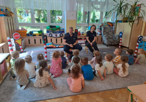 Funkcjonariusze Straży Miejskiej rozmawiają z dziećmi na temat bezpiecznego poruszania się po drodze.