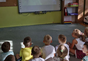 Dzieci oglądają film edukacyjny na temat mrówek.