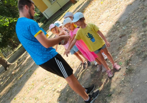 Trener żegna się z dziećmi- stempluje kolejno dzieciom znak drużyny Kangura na ręku.