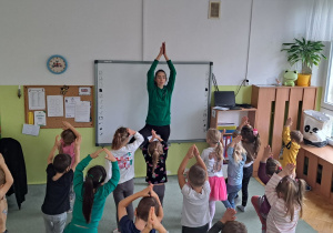 Dzieci powtarzają pozycję jogi po pani instruktorce.