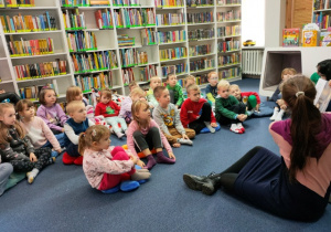 Dzieci z uwaga słuchają bajki czytanej przez panią bibliotekarkę.