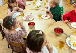 Dzieci z apetytem zjadają przygotowane przez siebie kanapki.