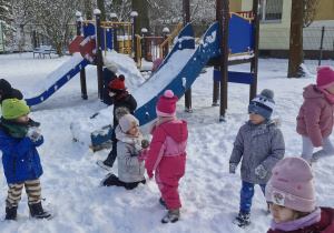 Dzieci bawią się na śniegu w przedszkolnym ogrodzie.