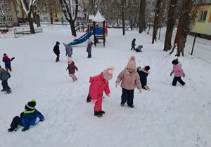 Dzieci biegają po ogrodzie przedszkolnym.