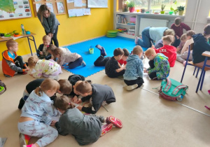 Dzieci w zespołach rówieśniczych rysują na dużych kartonach.