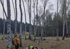 Dzieci leżą na kocach i nasłuchują dźwięków lasu.
